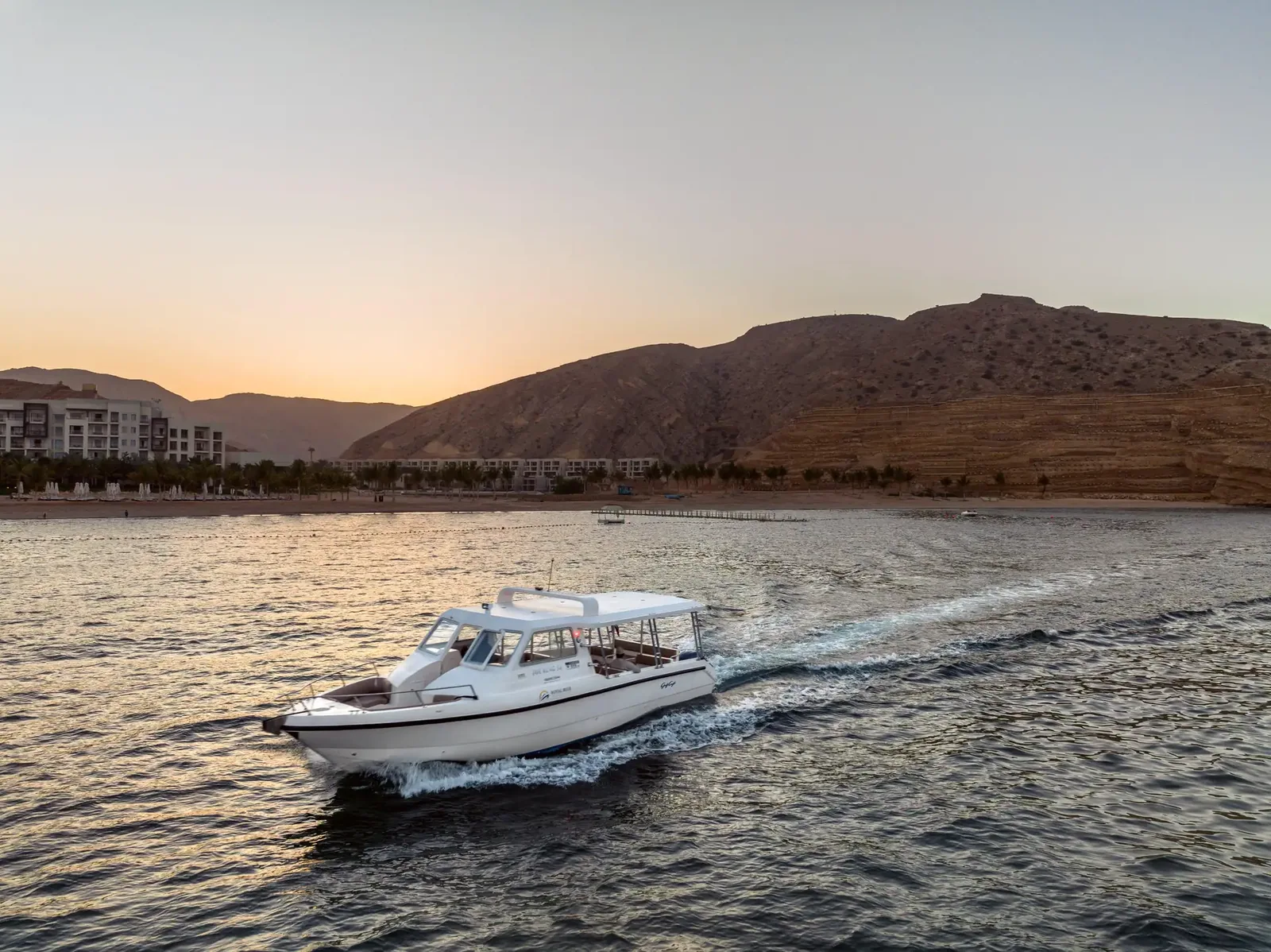 A motorboat on the Muscat coast in evening light