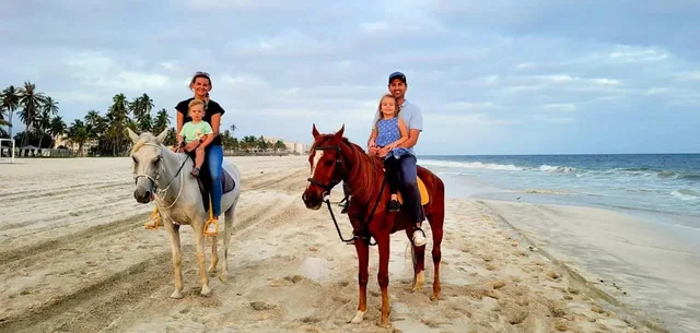 Family horse riding along Salalah beach