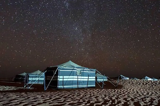 A tent beneath a star-filled desert sky; camp arrangement to confirm