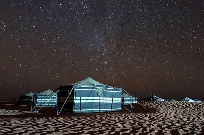 A tent beneath a star-filled desert sky; camp arrangement to confirm