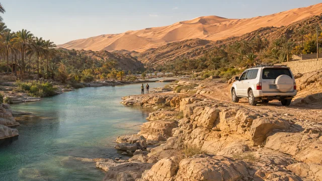 Wadi landscape, palms and a 4x4 beside desert dunes