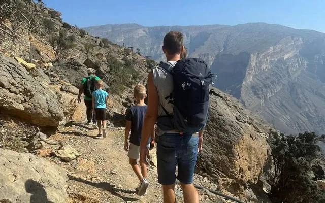 Walkers on a narrow mountain path above a canyon